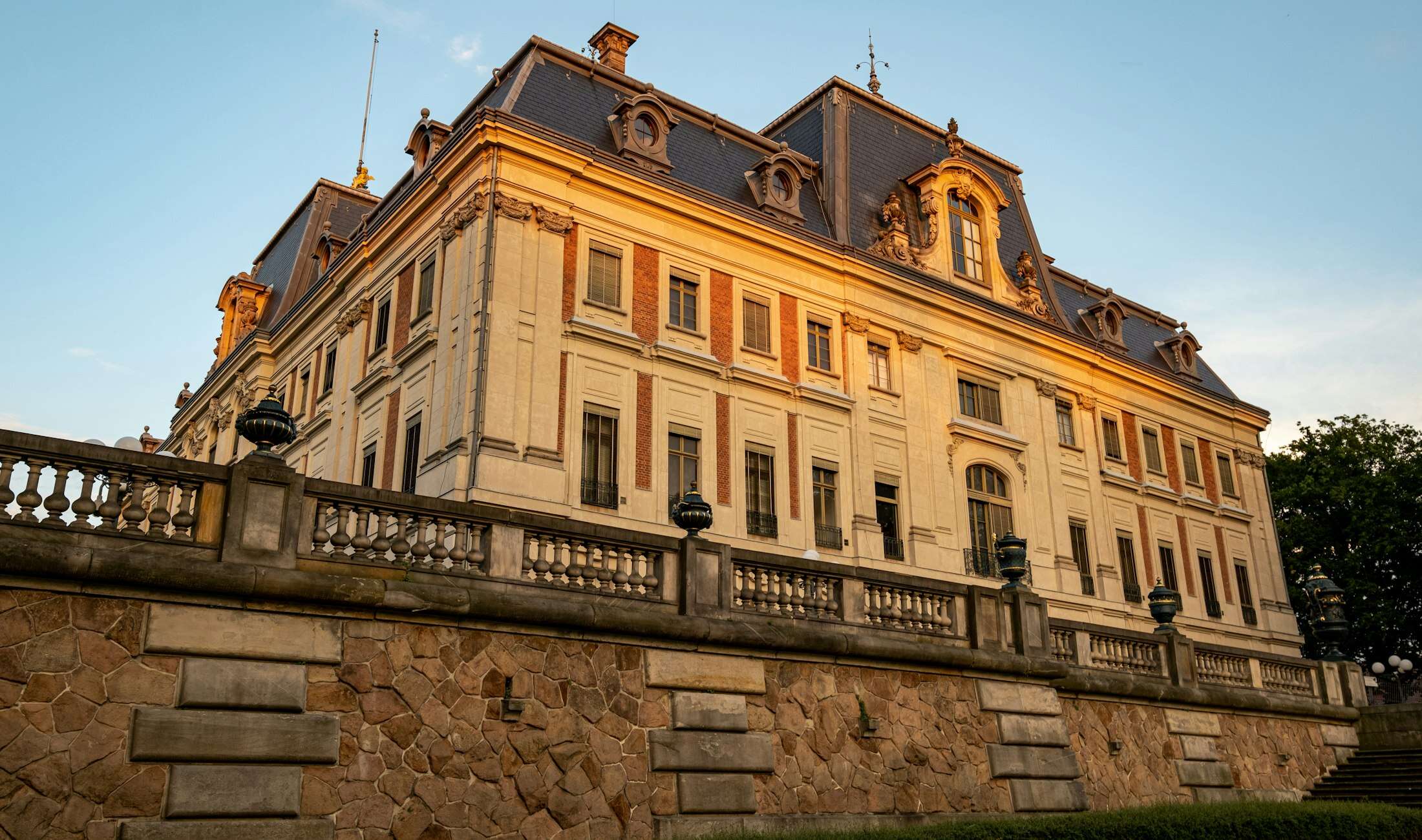 Façade d’un château classique au soleil couchant, terrasse à balustres