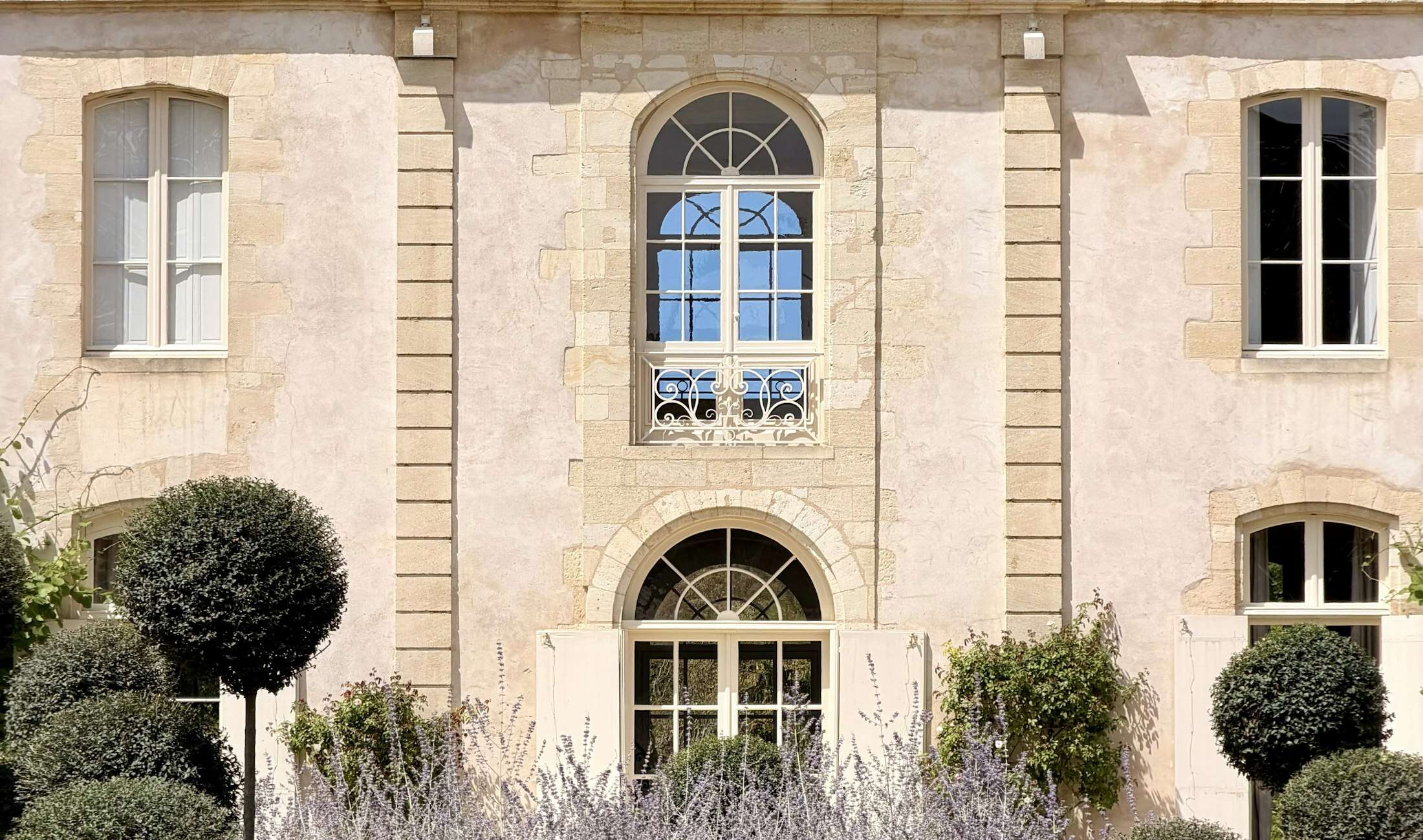 Façade de château en pierre, buis taillés